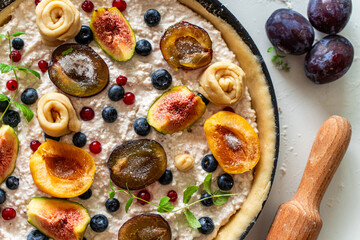 Raw tart or open summer pie with figs, prunes, apricots and blueberries is ready to bake in a round mold. Close-up. View from above. High quality photo