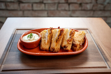 Delicious grilled cheese sandwiches with creamy dip on rustic wooden table