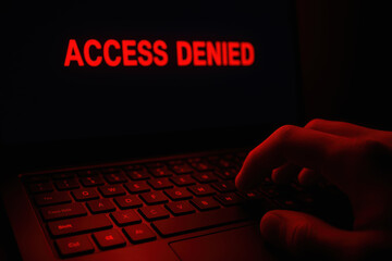 ACCESS denied warning on laptop keyboard with hand and red light multi factor authentication password security message conveying restricted access and cyber threat