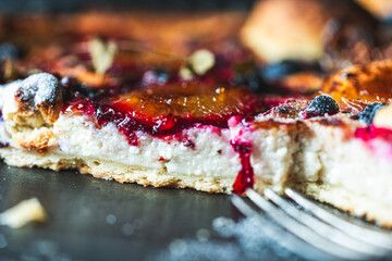 A delicious berry dessert, a piece of tart or an open sweet pie with figs, blueberries and apricots on a black plate. High quality photo