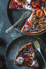 A delicious berry dessert, a piece of tart or an open sweet pie with figs, blueberries and apricots on a black plate. High quality photo