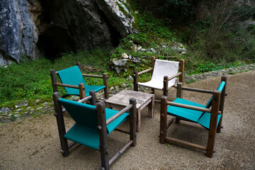 Outdoor seating area with wooden chairs and table surrounded by nature in a serene rocky landscape