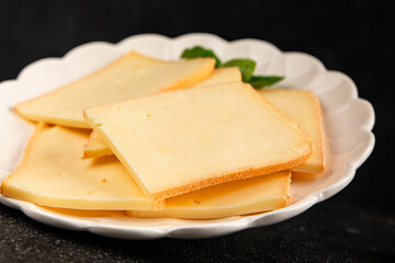 Raclette cheese portion slicing natural product tasty snack fresh delicious gourmet food background on the table rustic top view copy space