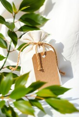 White fabric bag with tag and green leaves
