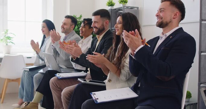 Group of happy confident business people sitting in a row in office applauding on a meeting or seminar to speaker. Successful company employees clapping hands at the conference. 4k video.
