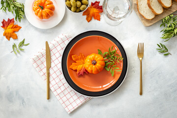 Festive Thanksgiving table setting with pumpkins and plate, cutlery and napkin - autumn leaves and...