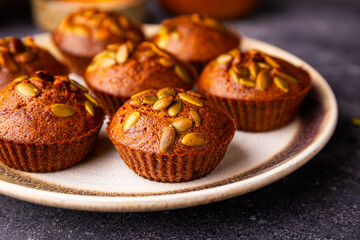 Autumn pumpkin cupcakes or baked muffins with fresh pumpkin and pumpkin seeds for Thanksgiving day close up