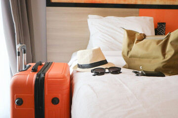 Orange Luggage with hat in modern hotel room after door opening. Baggage for Time to travel, service, journey, trip, summer holiday and vacation concepts