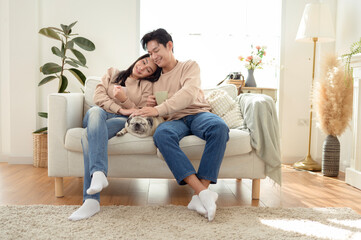 Young Couple Enjoys Playful Moment With Pet Dog in Cozy Living Room Setting During Afternoon