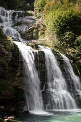 Scenic Waterfall in the Swiss Alps, Switzerland. Beautiful waterfall in the Swiss Alps, Switzerland, surrounded by mountains and nature. Scenic alpine landscape with flowing water, rocks, and forest, 