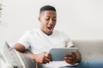 Black men wearing white shirt on sofa holding tablet