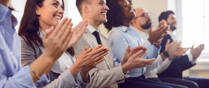 Happy group of multicultural business people sitting in a row clapping their hands. Concept congratulations in the company, employee engagement, business meeting, career strategy, event
