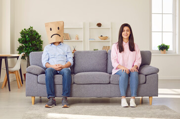 Couple family problems, man wearing paper bag head face to express negative emotion, insulting and offensive wife, feeling sad, suffering from bad relationship or break up, feeling lonely and sad