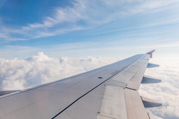 Obraz premium View from the airplane window at a beautiful cloudy sky and the airplane wing