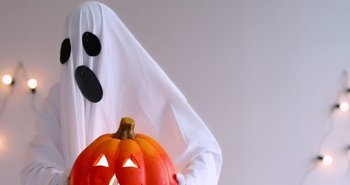 Halloween happy funny white ghost robe costume man dancing holding pumpkin lantern light scary smiling face, cosplay party costume for dress up fun, masquerade, stage performance and themed parties