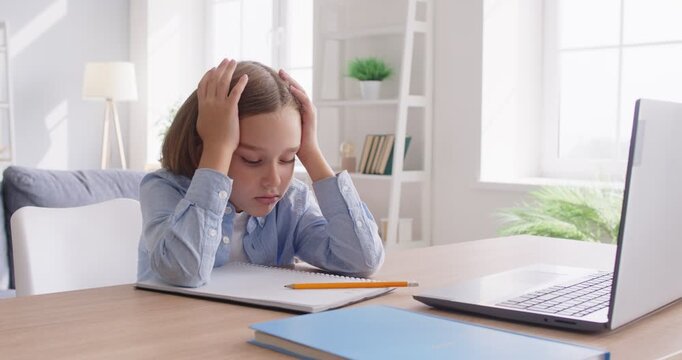 Elementary school child boy with dyslexia or dysgraphia learning problem sitting at desk with homework stops writing, worries about failing assignment, feels desperate, frustrated, angry, disappointed