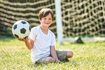 Naklejka premium kid play football or soccer on a outdoor field