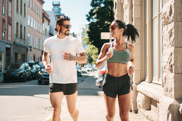 Young fitness couple running on a city on summer day