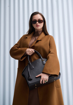Girl model in stylish clothes with bag posing in studio