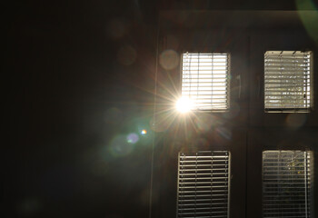 Sun shining through window blinds in room interior. Sunlight through the window frame Bokeh behind Office  metal iron jalousie.  room lighting range control. Sun rays beams through the window. sunbeam