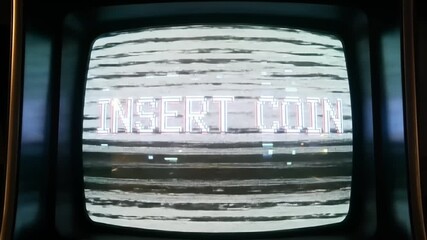 Close-up of a retro arcade game screen with 'INSERT COIN' text amidst static and glitch effects.