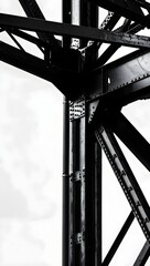 Monochrome steel bridge structure with rivets and beams against a cloudy sky backgroun