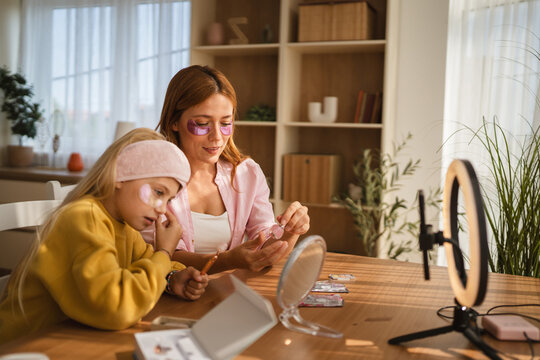 Mother and daughter applying makeup at home with ring light