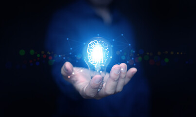 Hand holding glowing light bulb with brain and digital network lines symbolizing artificial intelligence, innovation, smart technology, knowledge, and futuristic business solutions.