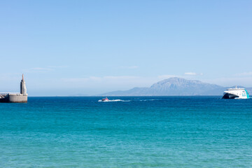 View of Gibraltar Strait with lighthouse, ferry, and Morocco. Tarifa. Spain. September 2025.