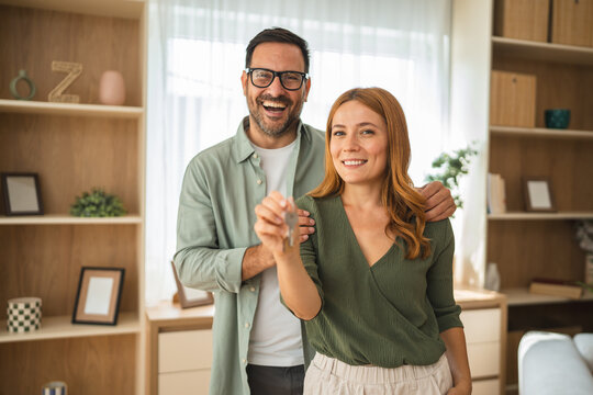 Happy couple showing new house keys in living room