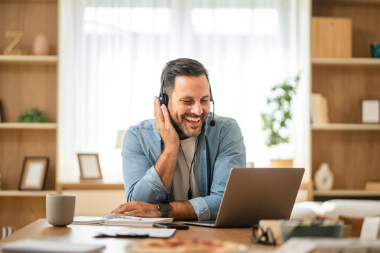Happy businessman working from home having a video call with headset - Powered by Adobe