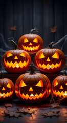 A close-up, vertical shot of several carved jack-o'-lanterns glowing in a dark, spooky setting with scattered autumn leaves and spiderwebs.