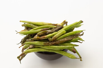 Rotten green beans in black bowl isolated on white background.