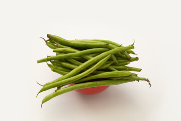 Fresh green beans in red bowl isolated on white background.