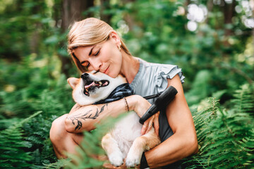 Happy woman with her Shiba Inu dog in the forest on summer season