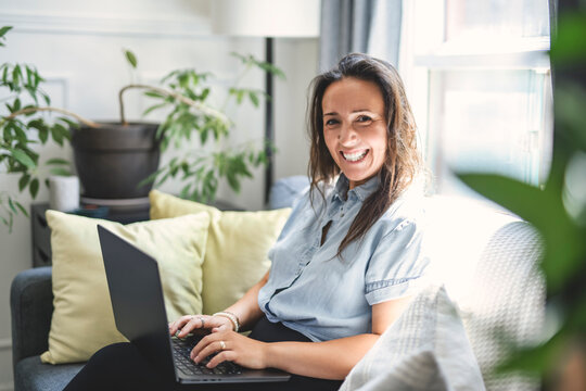 woman sitting surfing the internet on a laptop computer on a sofa at home