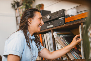 young woman putting on a vinyl record at home
