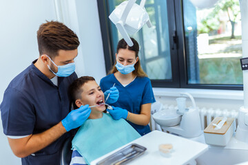 Obraz premium Dentist and Nurse Treating Boy’s Teeth in Modern Dental Clinic