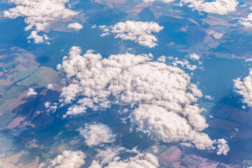 Aerial view from airplane window above green ground. View from the airplane window with beautiful clouds at sunrise