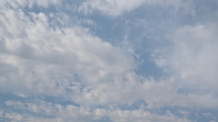 Blue sky with scattered white cirrus clouds. The clouds vary in size and shape, creating a serene atmosphere. Background light blue