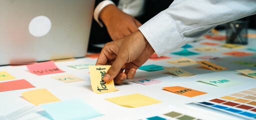 Fototapeta premium A vibrant workspace featuring colorful sticky notes and laptops where individuals engage in brainstorming and collaborative project planning, fostering creativity and teamwork. SACTR
