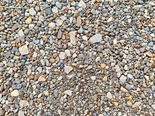 Natural gravel surface with a variety of stones creating a textured background for design and text placement