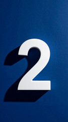 White number 2 two on deep blue background. Gentle shadow adds contrast and dimension.