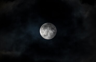 Full moon surrounded by dark clouds in a night sky creating a dramatic scene