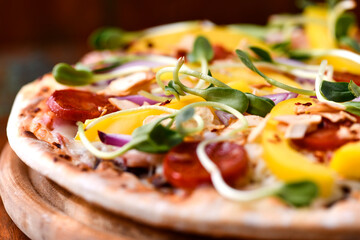 Pizza with chorizo ​​sausage, mozzarella cheese and yellow pepper. Rustic wooden background. Soft focus.	
