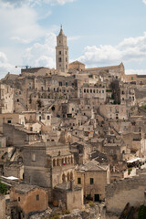 Obraz premium Historic stone city of Matera, Italy. Ancient cave dwellings and medieval architecture built into the rock, UNESCO World Heritage site. Panoramic view with dramatic sky.