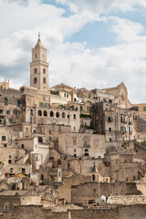 Fototapeta premium Historic stone city of Matera, Italy. Ancient cave dwellings and medieval architecture built into the rock, UNESCO World Heritage site. Panoramic view with dramatic sky.