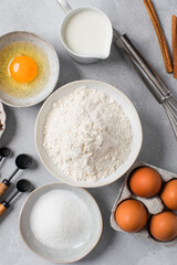 Baking ingredients flat lay with flour, eggs, sugar, and spices on marble surface