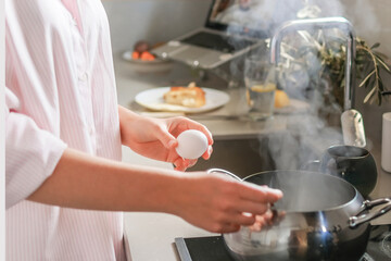 Young woman working remotely from the kitchen, balancing cooking and video call, enjoying mindful morning routine and modern lifestyle. Home office, wellness, healthy habits.