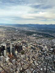 aerial view of downtown Los Angeles - airplane view of Southern California city skyline and mountains in the distance, cloudy summer sky